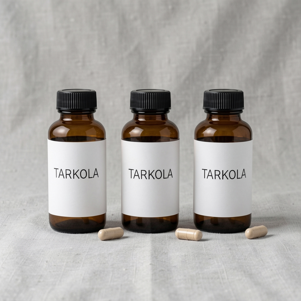 Pelantra three-product range arranged on a light grey linen surface — amber glass bottles with minimal black label typography, single capsule beside each bottle under controlled studio lighting